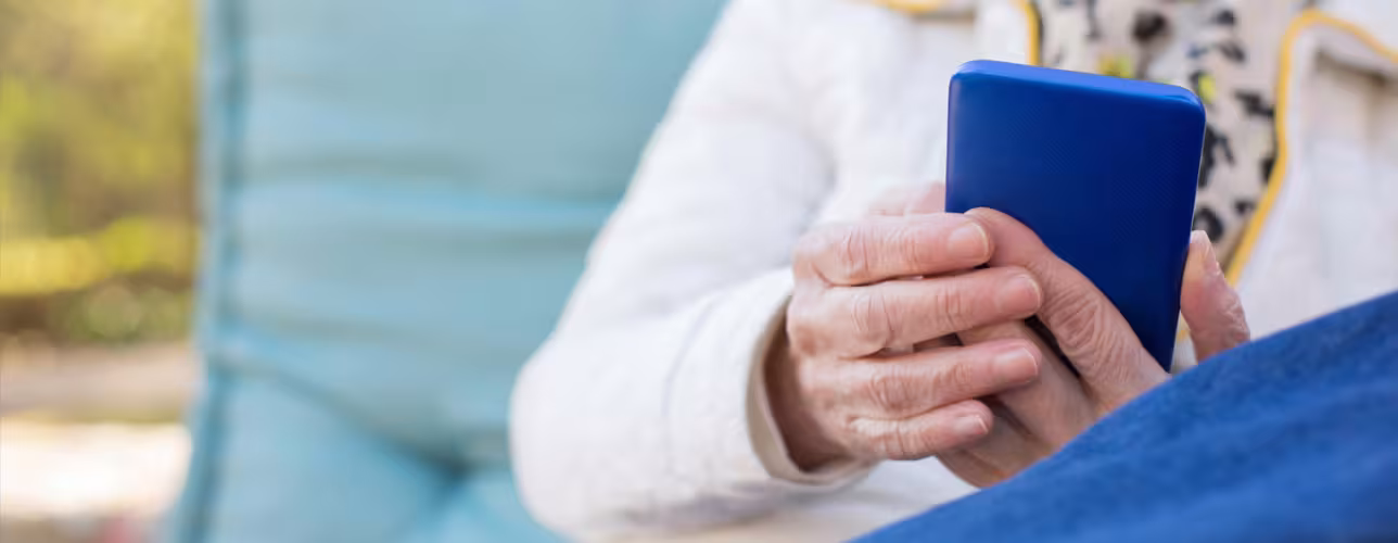 Mujer mayor mira la pantalla de un teléfono móvil azul oscuro