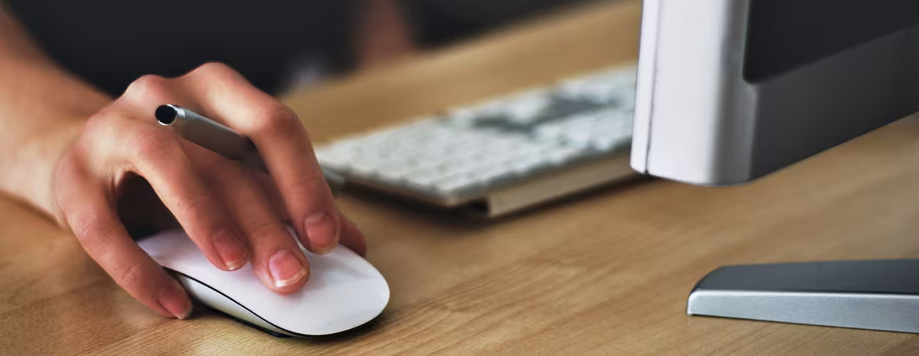 Mano utilizando un ratón de ordenador como representación de la formación y las competencias digitales.