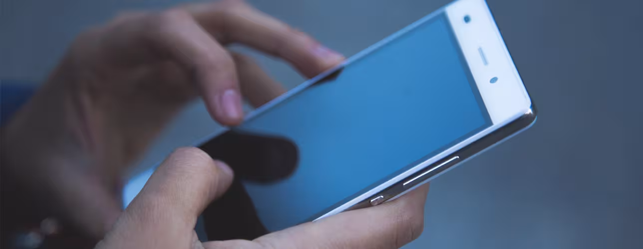Primer plano de unas manos utilizando un teléfono móvil con pantalla táctil